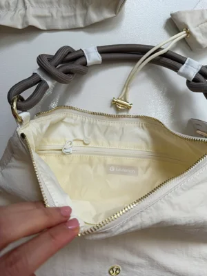 کیف کانورتیبل Lululemon شیری؛ محفظه اصلی باز و جیب زیپ‌دار داخل با آستر روشن