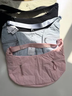 کیف اسلوچی اسلینگ Lululemon 13L؛ ردیف رنگ‌های شیری، مشکی، آبی و صورتی روی سطح روشن