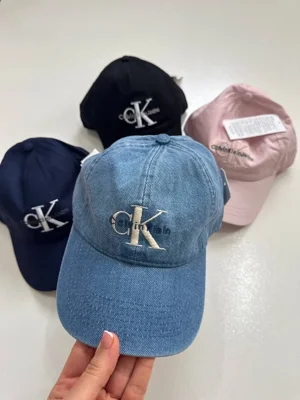 نمای جلوی کلاه بال کپ Calvin Klein Jeans آبی با ظاهر جین و لوگوی CK، کنار رنگ‌های دیگر