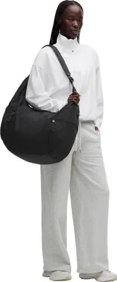 کیف اسلوچی اسلینگ Lululemon 13L مشکی روی شانه مدل با لباس سفید و شلوار روشن