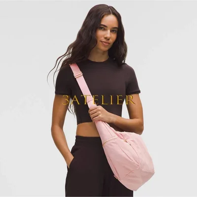 کیف اسلوچی اسلینگ Lululemon 13L صورتی روی شانه مدل با لباس مشکی و بند قابل تنظیم