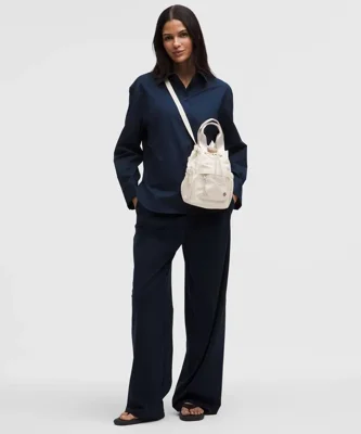 باکت بگ کانورتیبل مینی Lululemon 5L شیری روی مدل؛ نحوه حمل کراس‌بادی و نمای جلوی کیف