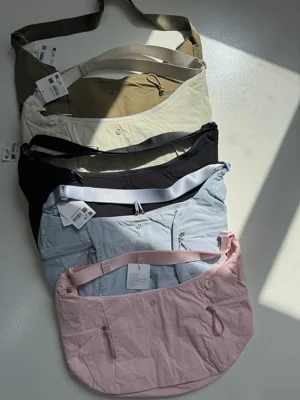 چیدمان رنگ‌های سبز زیتونی، شیری، مشکی، آبی آسمانی و صورتی کیف اسلوچی اسلینگ Lululemon 13L با جیب‌های زیپ‌دار جلو - تصویر دوم
