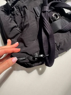 باکت بگ کانورتیبل مینی Lululemon 5L مشکی؛ نمای نزدیک اتصال بند در قسمت پایین پشت و بندهای حمل