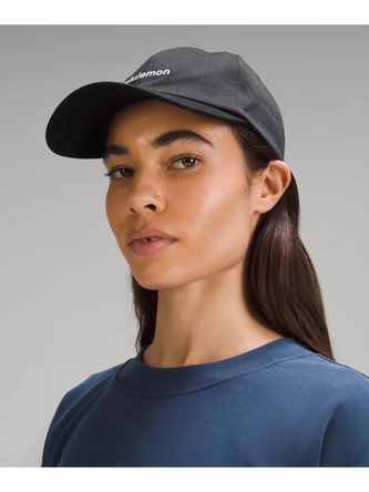 کلاه بال کپ Wordmark Lululemon، کلاه لبه‌دار خاکستری تیره روی سر مدل با تیشرت آبی