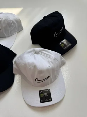 نمای رنگ‌بندی کلاه بال کپ Nike سفید و مشکی با لوگوی خطی Swoosh روی سطح روشن - تصویر دوم