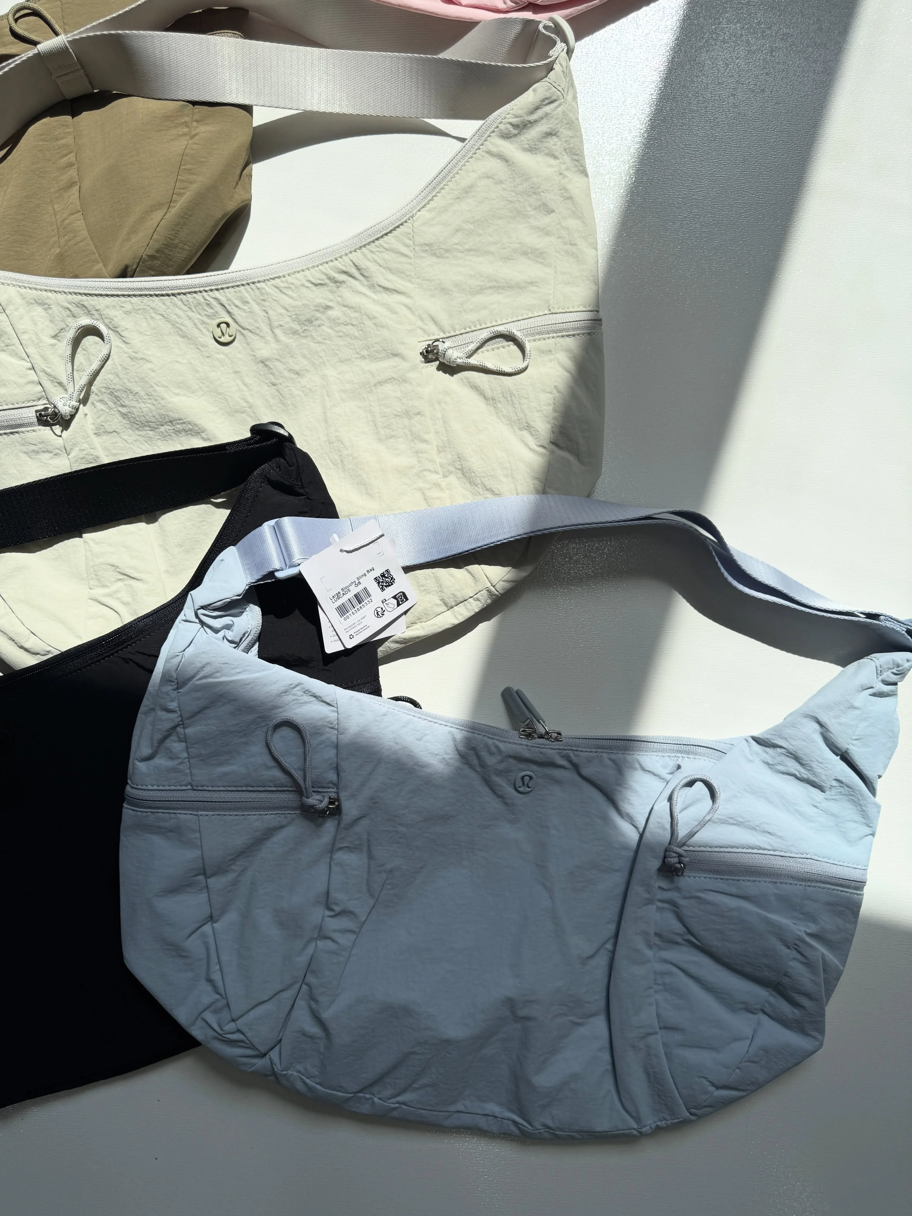 کیف اسلوچی اسلینگ Lululemon 13L آبی؛ نمای جلو و جیب‌ها کنار کیف شیری