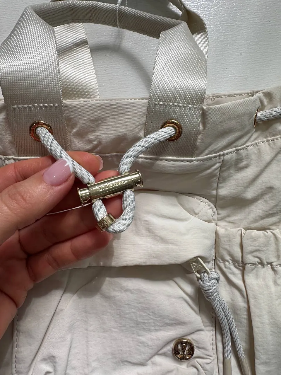 باکت بگ کانورتیبل مینی Lululemon 5L شیری؛ نمای نزدیک بند جمع‌شونده دهانه و قطعه فلزی تنظیم بند