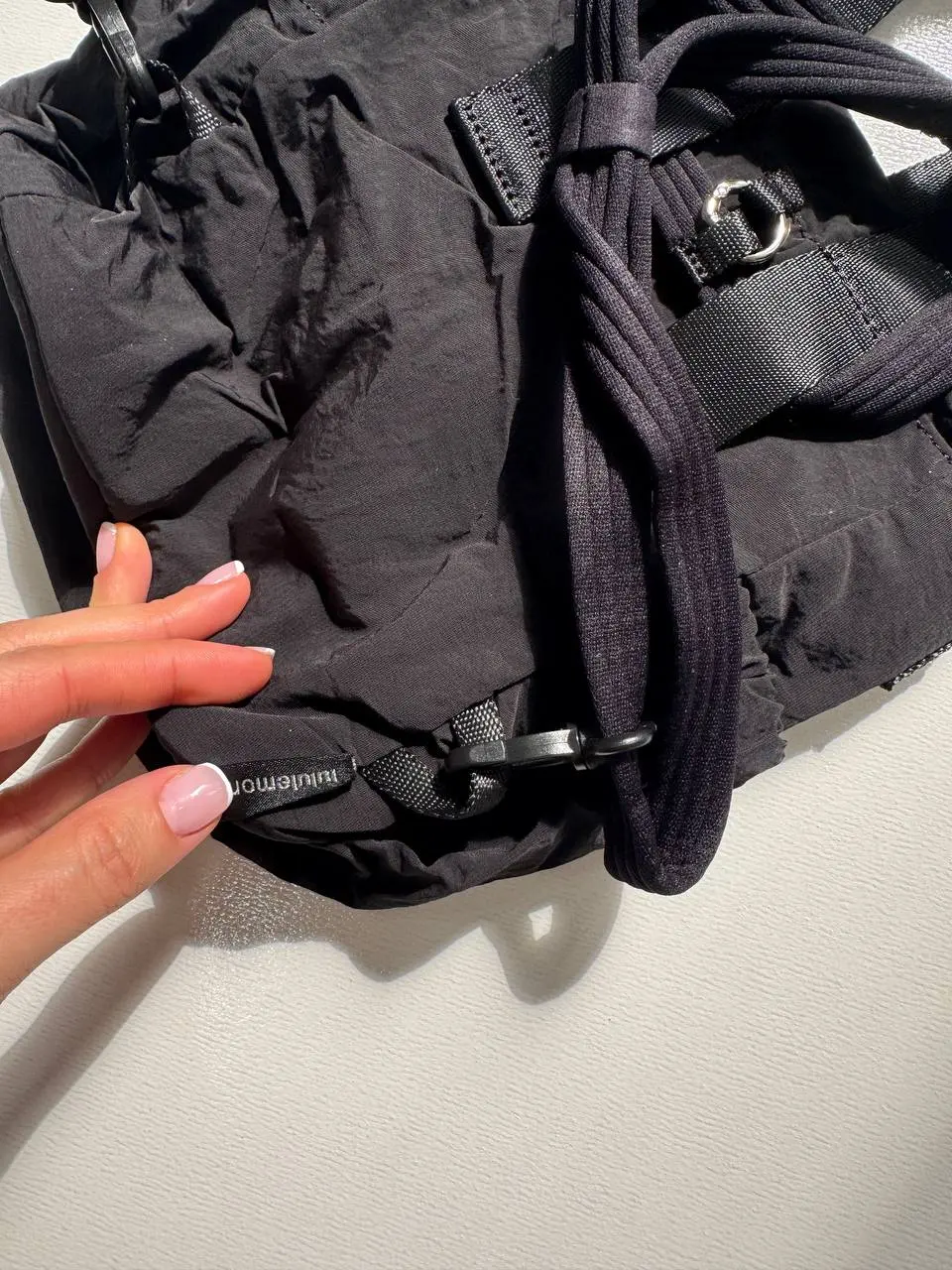 باکت بگ کانورتیبل مینی Lululemon 5L مشکی؛ نمای نزدیک اتصال بند در قسمت پایین پشت و بندهای حمل