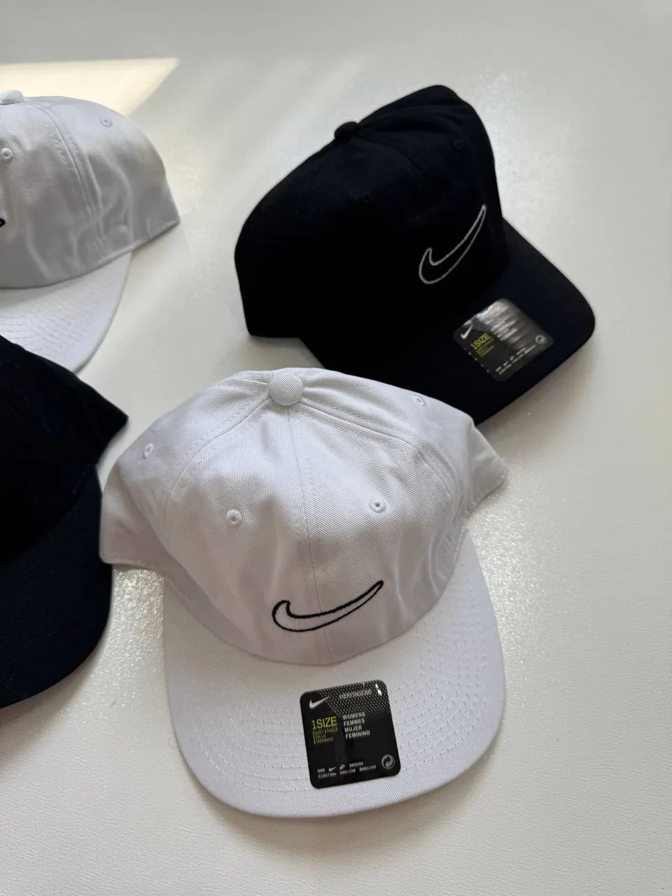 نمای رنگ‌بندی کلاه بال کپ Nike سفید و مشکی با لوگوی خطی Swoosh روی سطح روشن