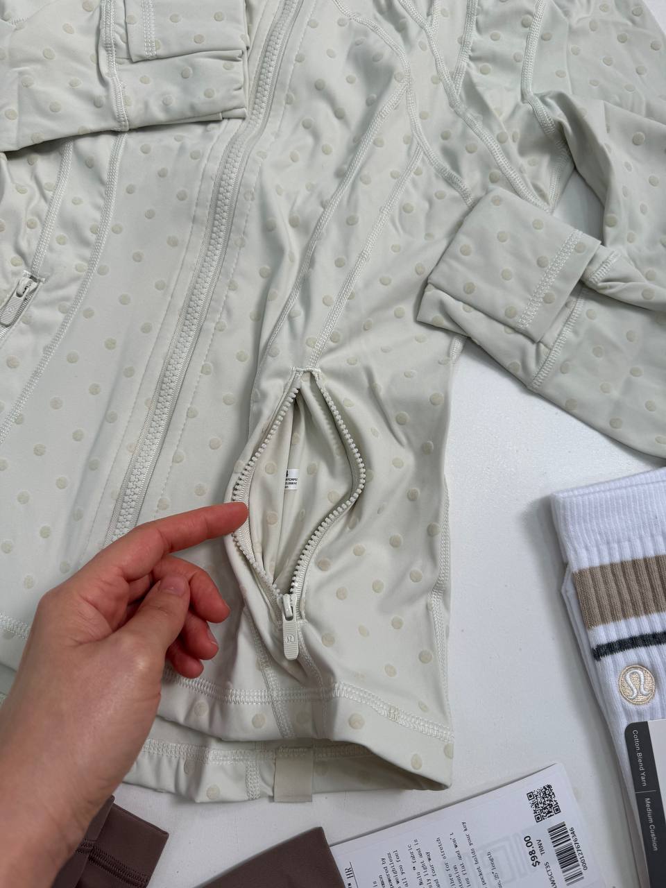 دیفاین جکت لون Lululemon، نمای نزدیک سرآستین و جای انگشت شست جکت خاکستری روشن طرح‌دار در دست