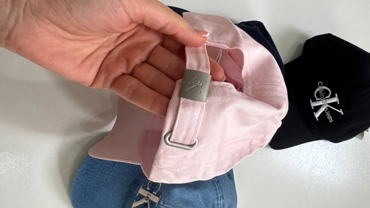جزئیات بند تنظیم و حلقه فلزی پشت کلاه بال کپ Calvin Klein صورتی در دست